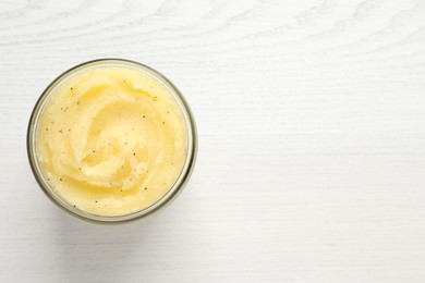 Body scrub in glass jar on white wooden table, top view. Space for text