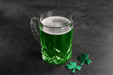 Photo of St. Patrick's day celebration. Green beer with decorative clover leaves on grey table