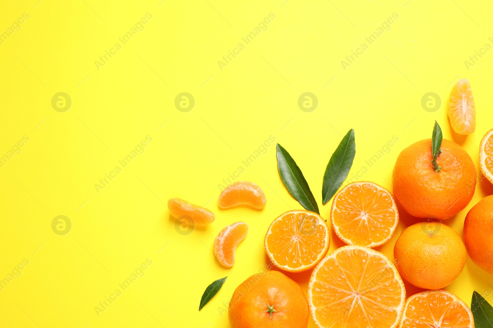 Photo of Flat lay composition with fresh ripe tangerines and leaves on yellow background, space for text. Citrus fruit