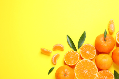 Photo of Flat lay composition with fresh ripe tangerines and leaves on yellow background, space for text. Citrus fruit