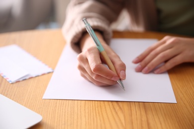 Photo of Woman writing letter at wooden table, closeup