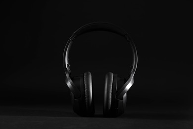 Photo of Stylish modern wireless headphones on black background