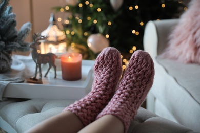 Woman wearing pink knitted socks in room decorated  for Christmas, closeup