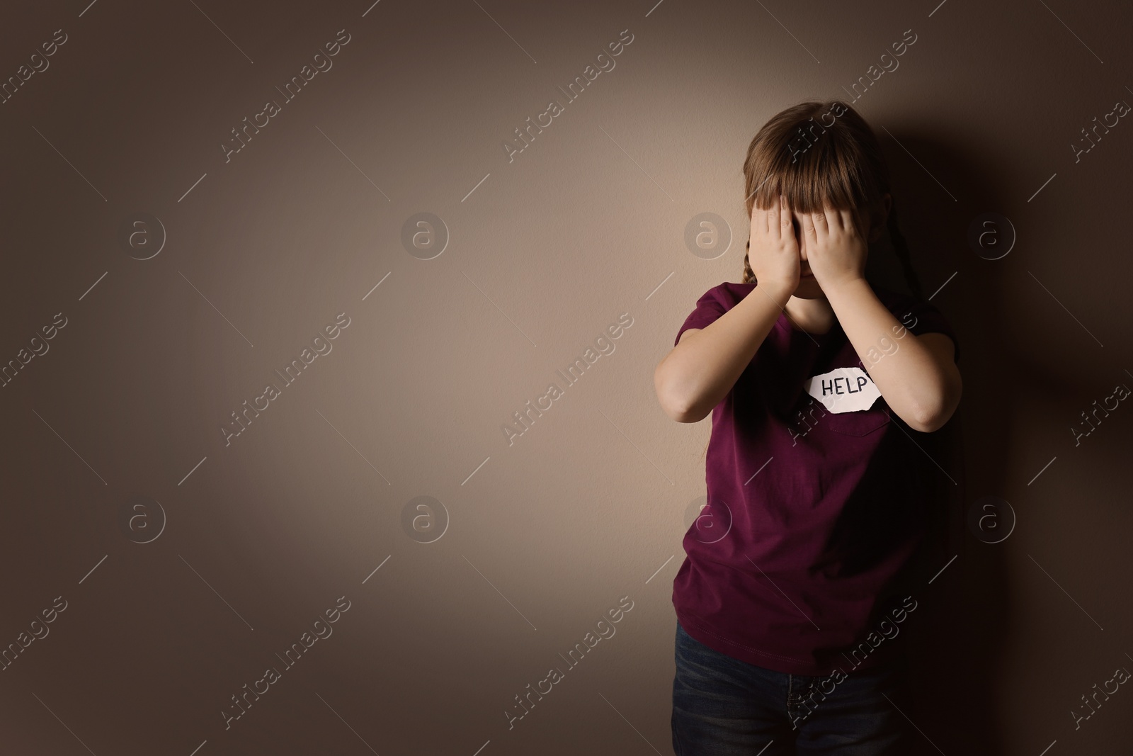 Photo of Little girl with sign HELP on beige background, space for text. Child in danger