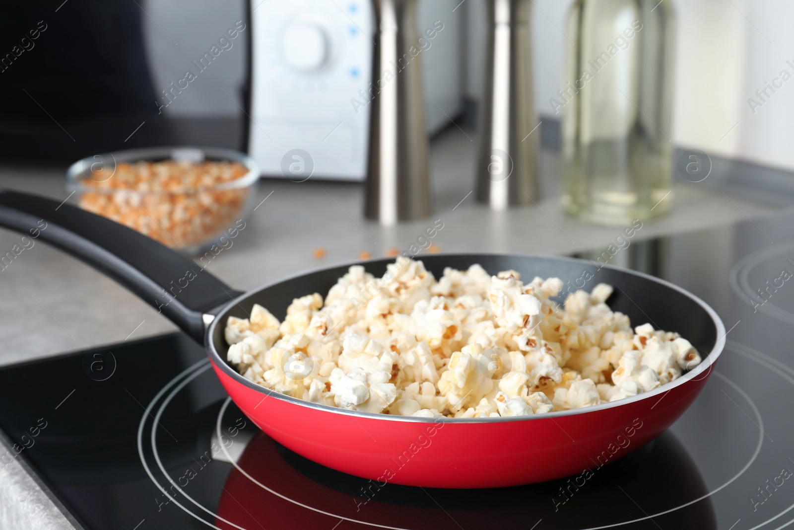 Photo of Frying pan with tasty popcorn on stove in kitchen