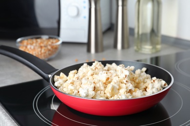 Frying pan with tasty popcorn on stove in kitchen