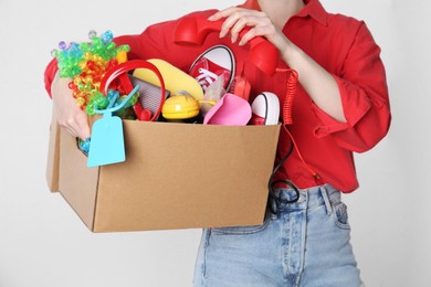 Woman holding box of unwanted stuff on white background, closeup