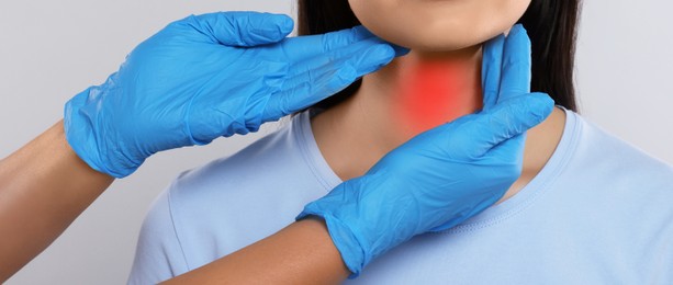 Endocrinologist examining thyroid gland of patient on light grey background, closeup. Banner design