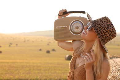 Photo of Happy hippie woman with radio receiver in field, space for text