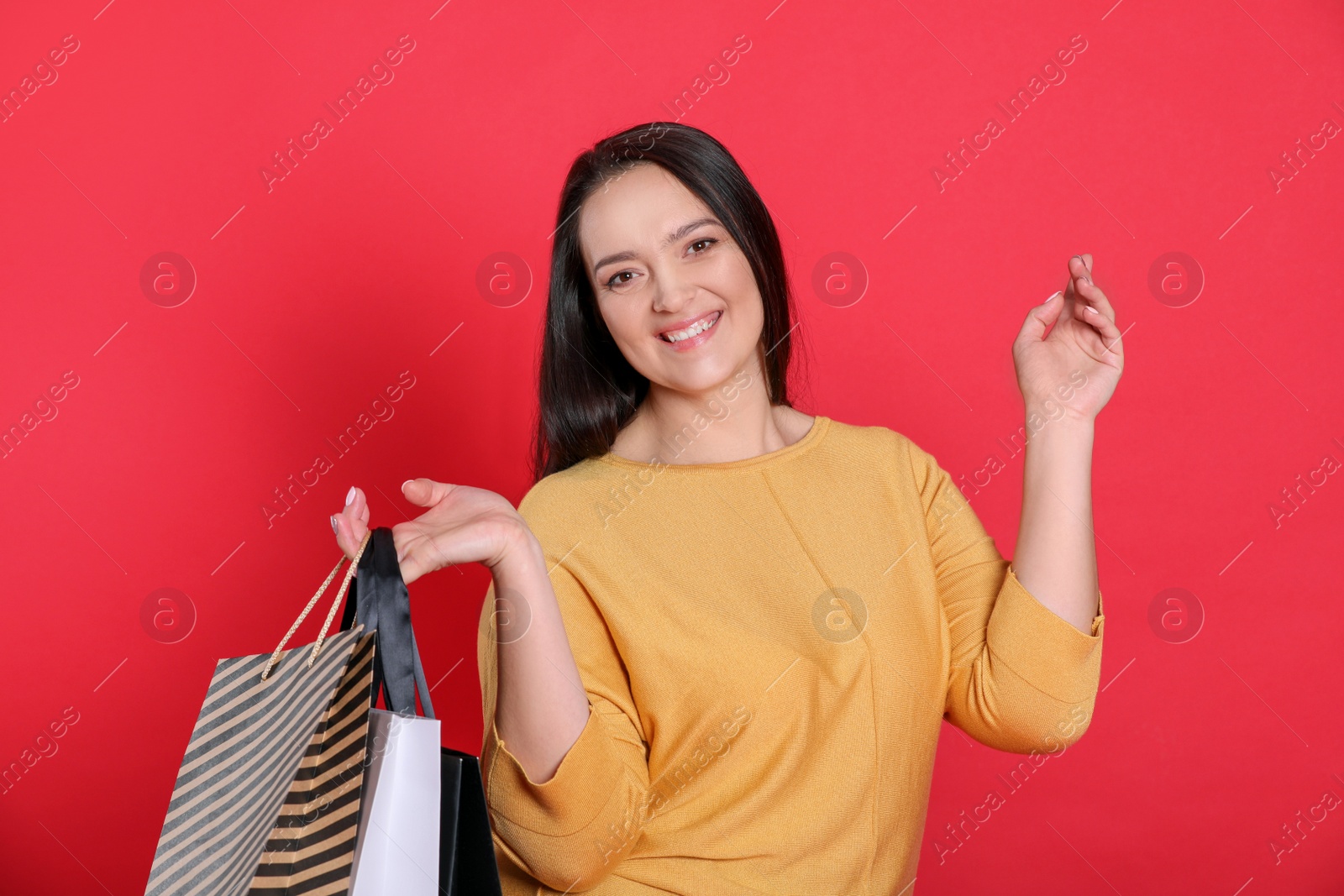 Photo of Beautiful overweight woman with shopping bags on red background