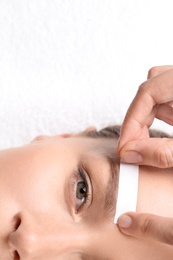 Photo of Young woman having eyebrow correction procedure in beauty salon, closeup