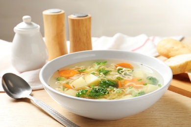 Photo of Bowl of fresh homemade vegetable soup served on wooden table