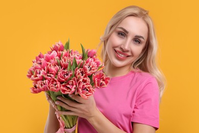 Photo of Happy young woman with beautiful bouquet on orange background