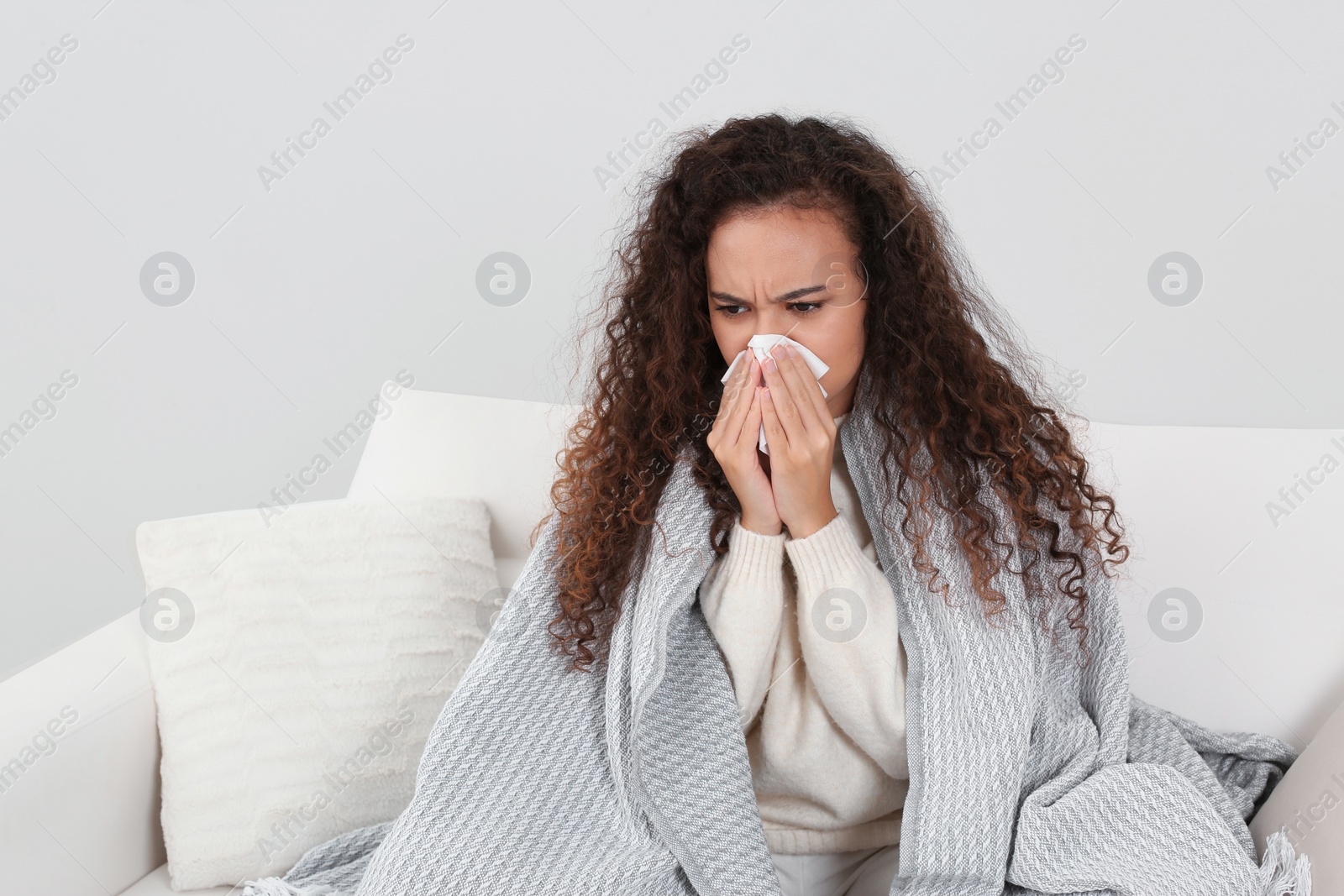 Photo of Sick African American woman with tissue at home