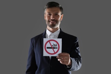 Photo of Man holding card with no smoking sign on gray background
