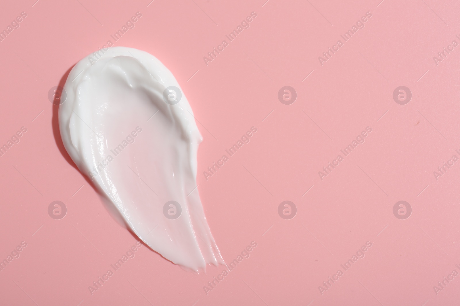 Photo of Sample of face cream on pink background, top view. Space for text