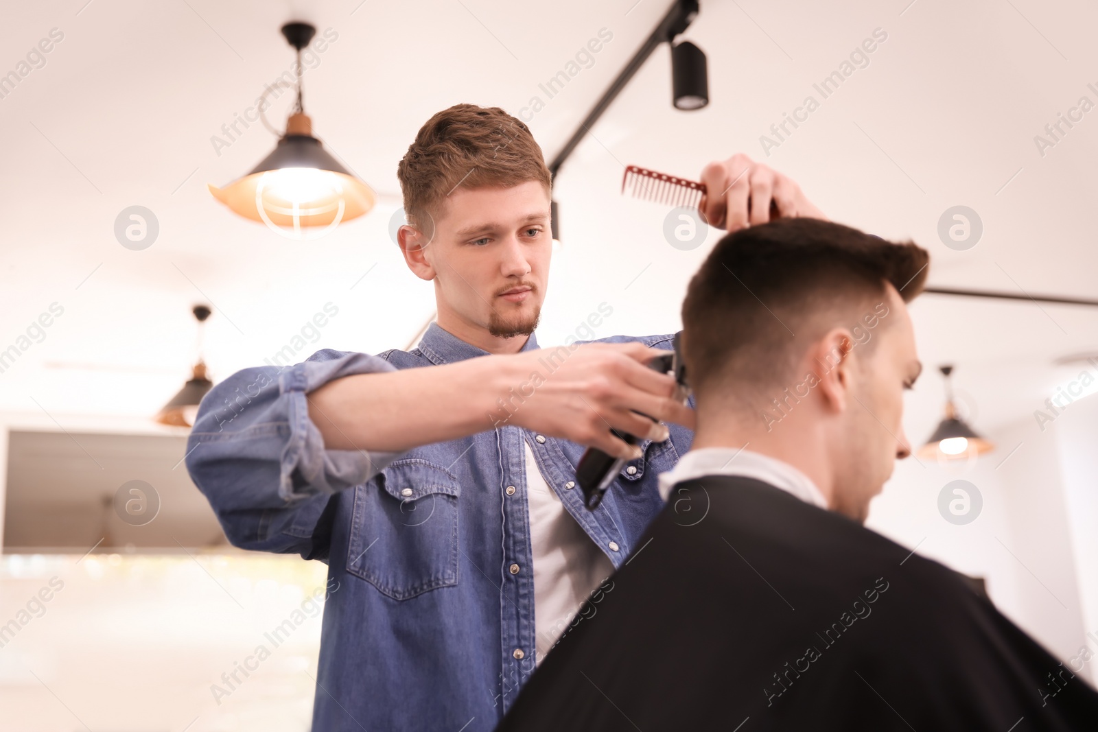 Photo of Professional barber working with client in hairdressing salon. Hipster fashion