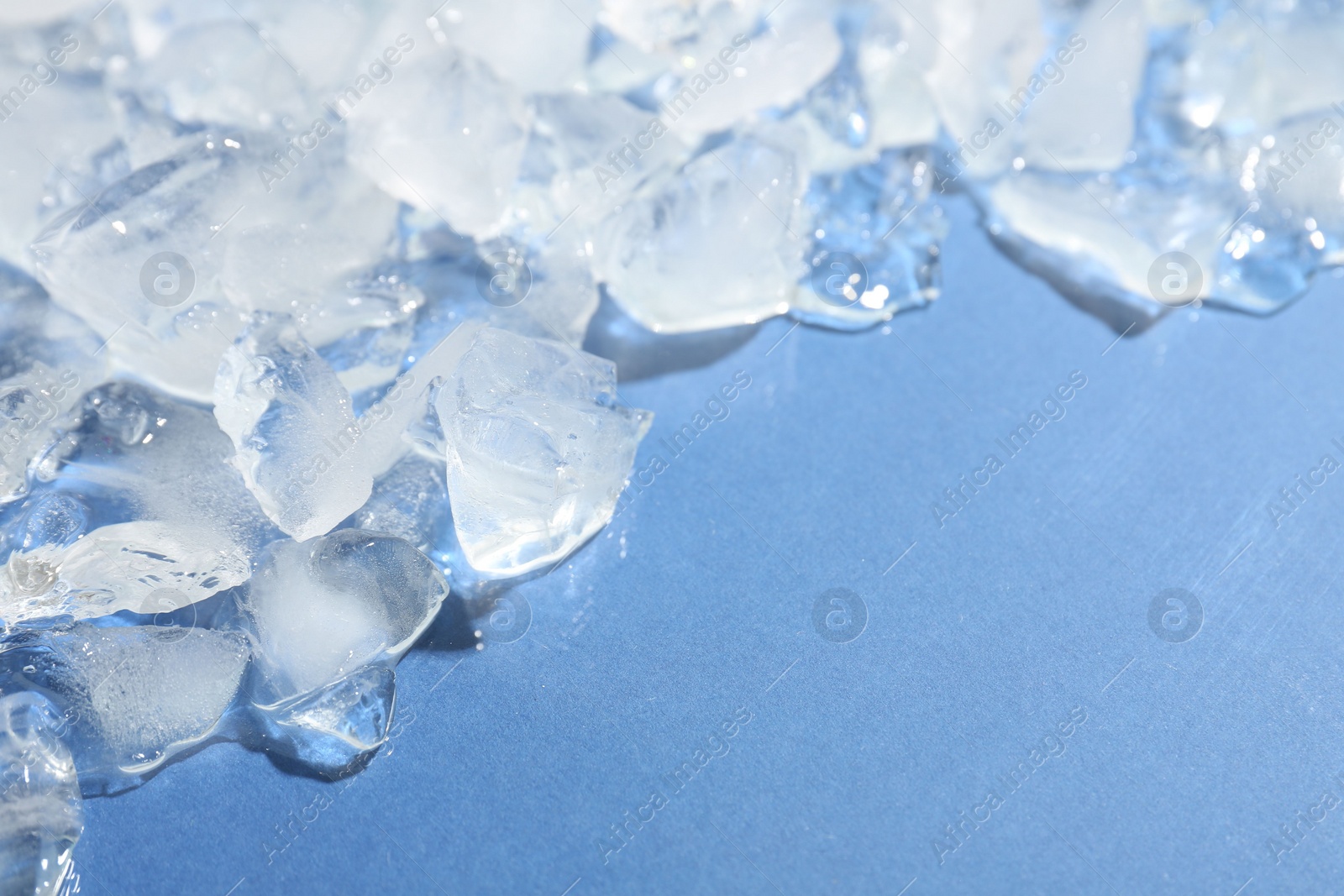 Photo of Pieces of crushed ice on light blue background, above view. Space for text