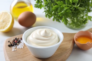 Photo of Tasty mayonnaise sauce in bowl, spices and ingredients on white table, closeup