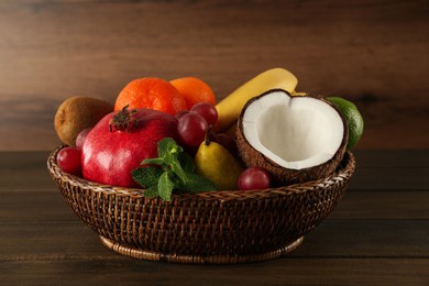 Photo of Fresh ripe fruits in wicker bowl on wooden table