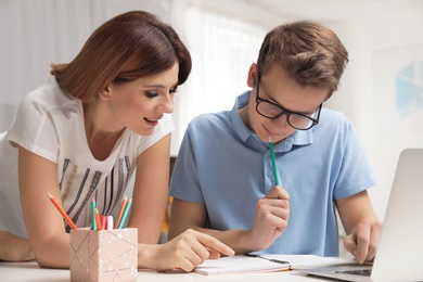 Photo of Mother helping her teenager son with homework indoors