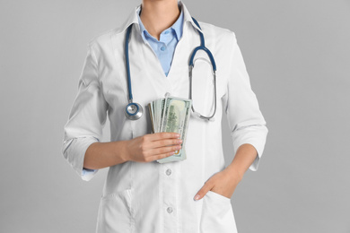 Photo of Doctor with bribe on grey background, closeup. Corruption in medicine