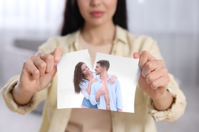 Photo of Woman ripping photo at home, focus on picture. Divorce concept