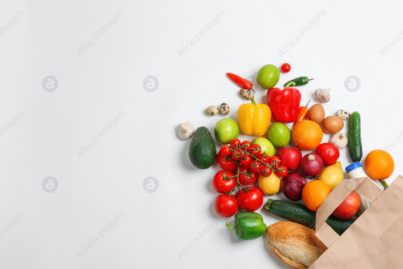 Photo of Paper bag with different groceries on white background, top view