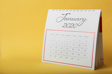 Photo of Paper calendar on yellow background, space for text. Planning concept