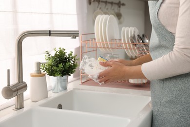 Photo of Woman washing glass at sink in kitchen, closeup