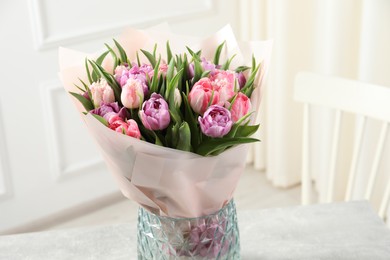 Vase with bouquet of beautiful tulips on table indoors, closeup