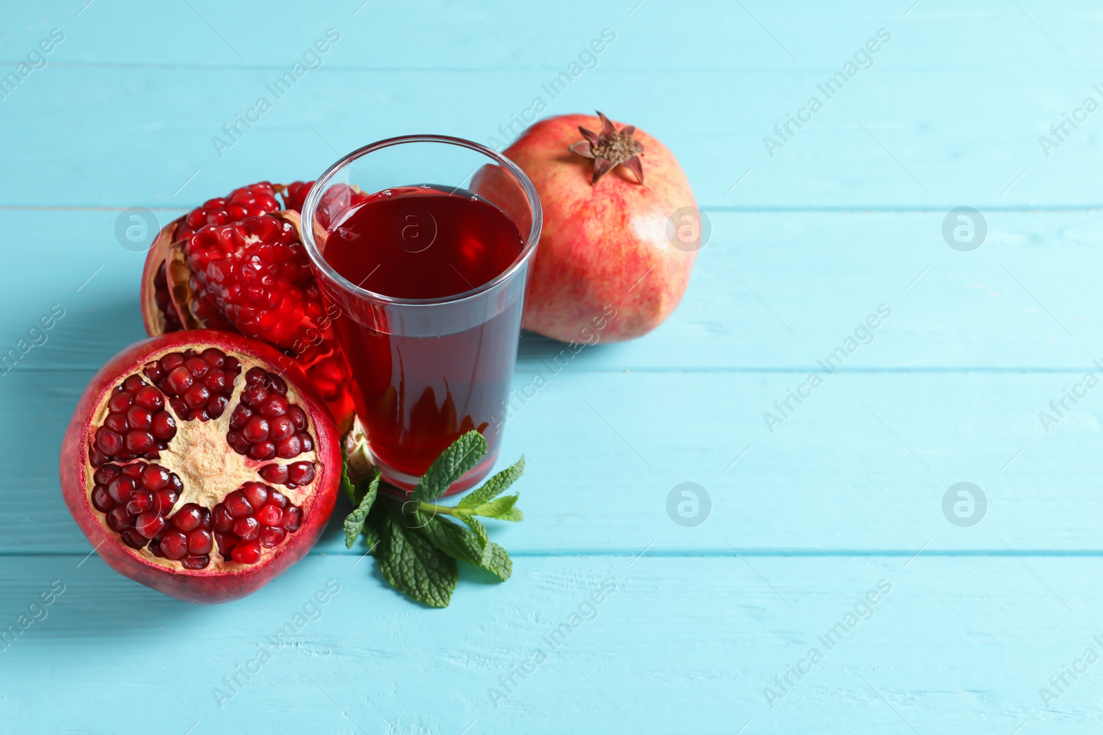 Photo of Glass of pomegranate juice and fresh fruits on wooden background, space for text