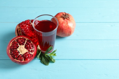 Photo of Glass of pomegranate juice and fresh fruits on wooden background, space for text