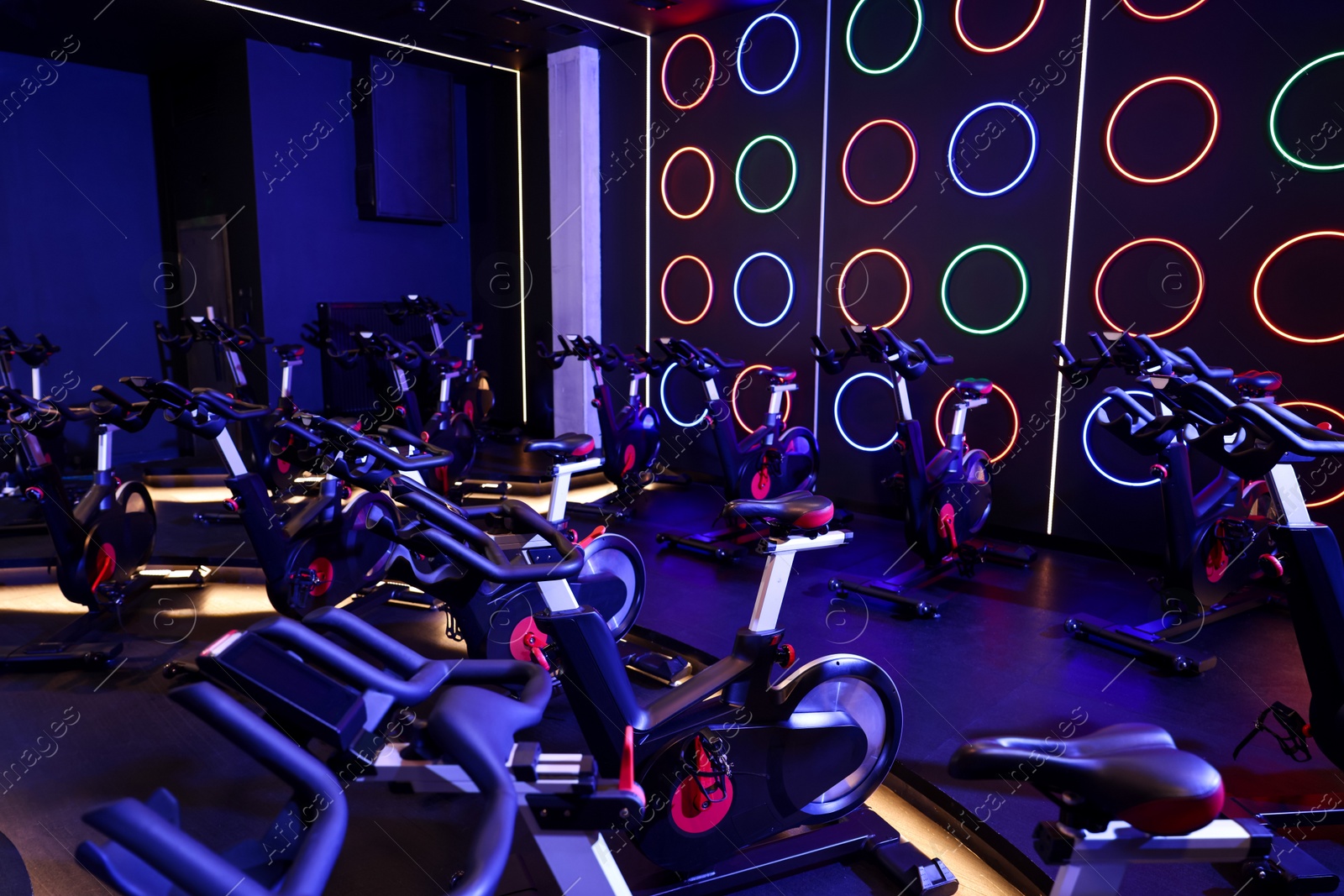 Photo of Many exercise bikes in fitness club. Indoor cycling class