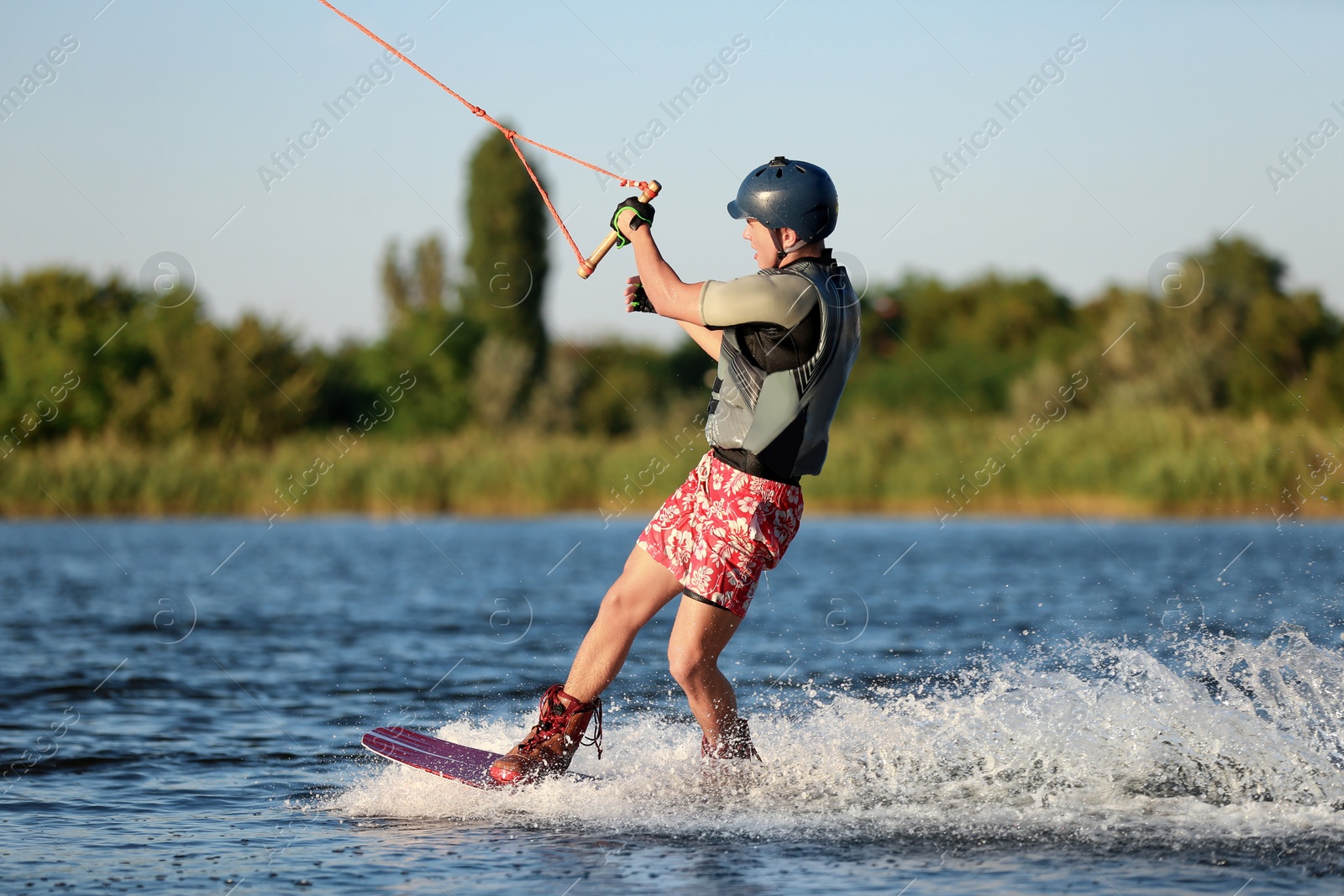 Photo of Teenage boy wakeboarding on river. Extreme water sport