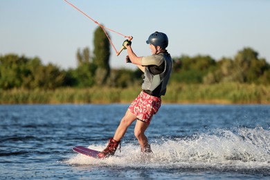 Photo of Teenage boy wakeboarding on river. Extreme water sport