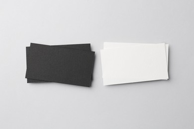 Photo of Blank black and white business cards on light background, flat lay. Mockup for design
