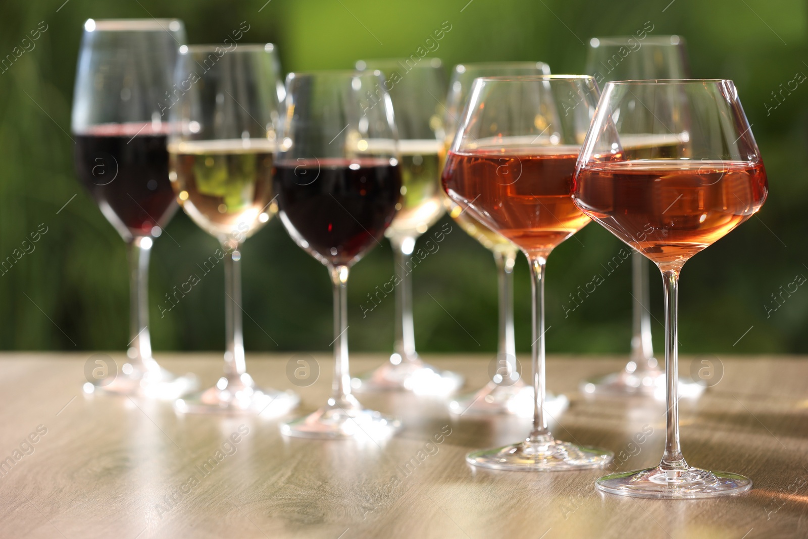 Photo of Different tasty wines in glasses on wooden table