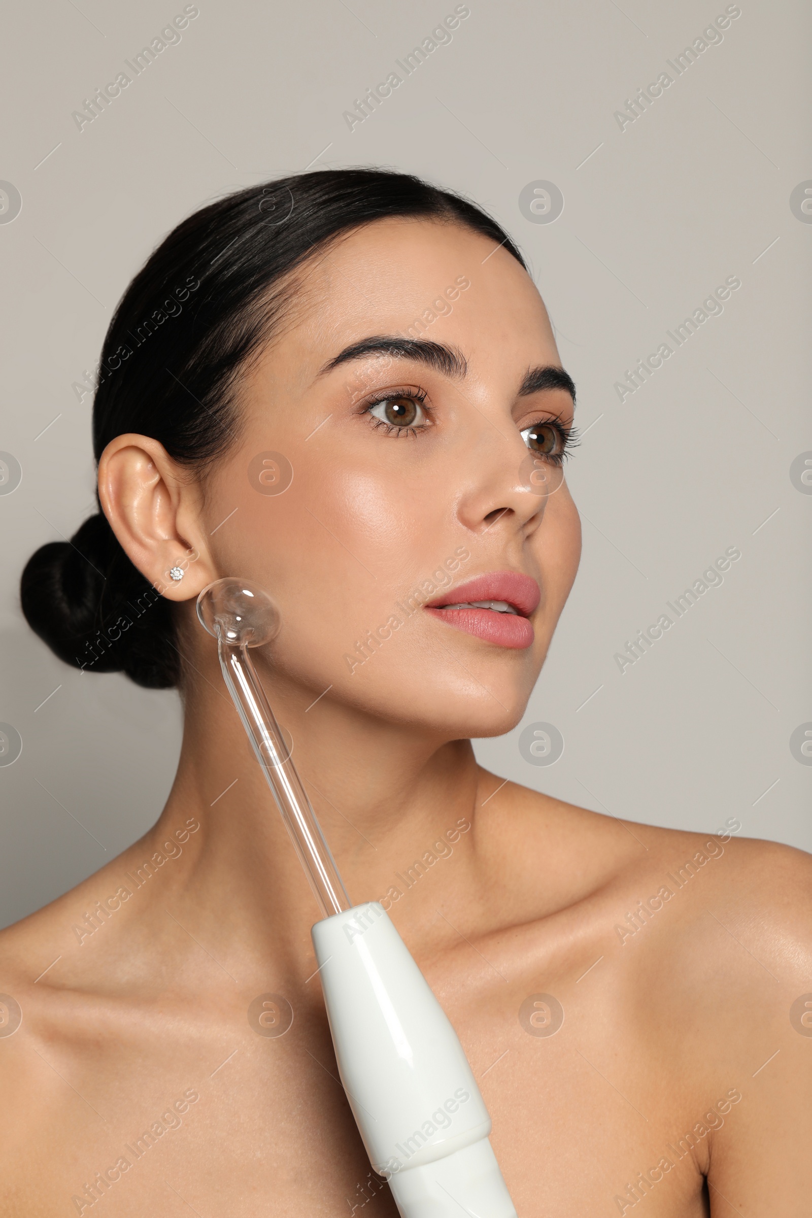 Photo of Woman using high frequency darsonval device on grey background