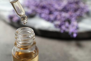 Photo of Dripping lavender essential oil into bottle, closeup. Space for text