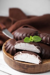 Photo of Delicious chocolate covered marshmallows with mint on white wooden table, closeup