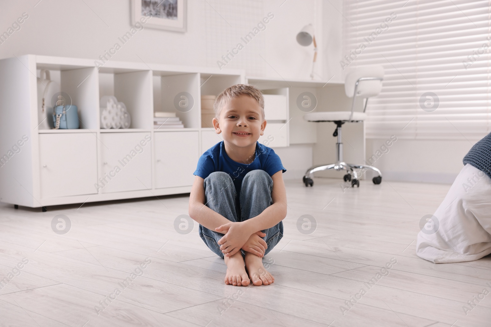 Photo of Cute little boy sitting on warm floor at home. Heating system