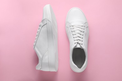 Pair of stylish white sneakers on pink background, top view