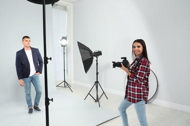 Photo of Professional photographer working with young man in modern studio