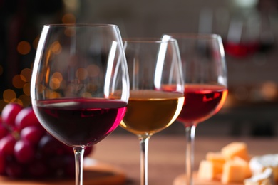 Glasses with different wines against blurred background, closeup