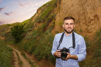 Photo of Male photographer with professional camera among green hills