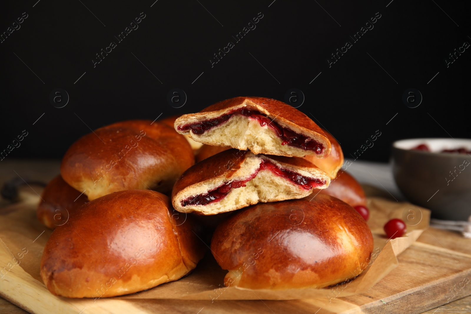 Photo of Delicious baked cranberry pirozhki on wooden table