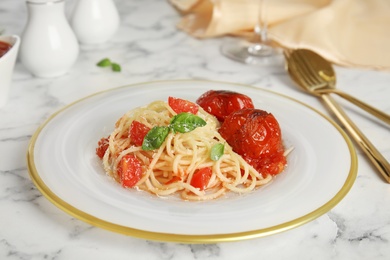 Photo of Tasty pasta with tomatoes, cheese and basil on white marble table