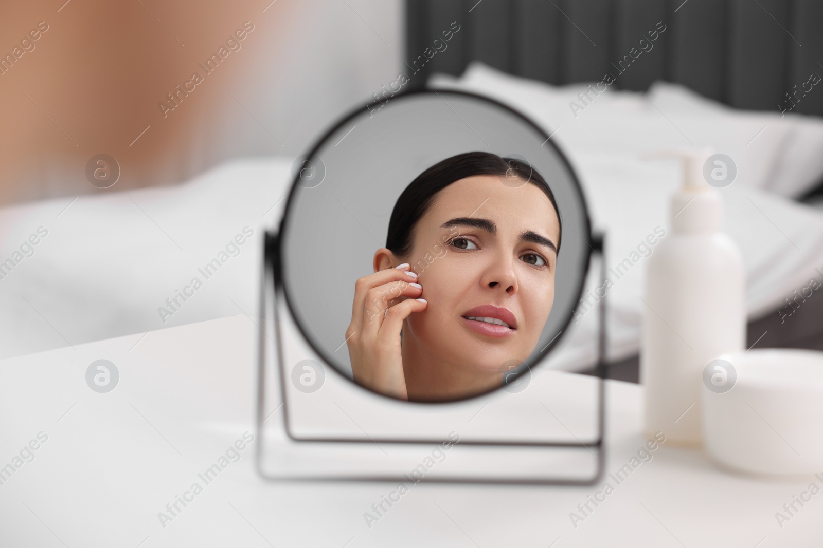 Photo of Woman with dry skin looking at mirror indoors