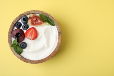 Photo of Bowl with yogurt, berries, fruits and mint on yellow background, top view. Space for text